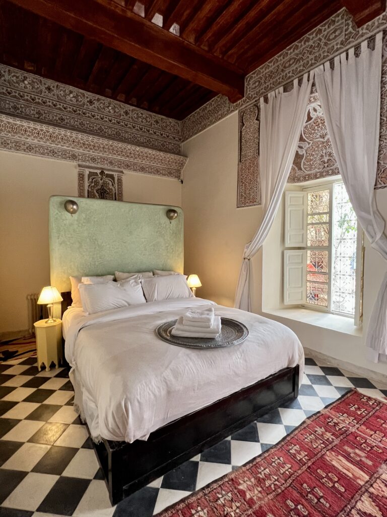 Riad Tizwa Marrakech room 6 view to the window, bed and traditional ornate plasterwork