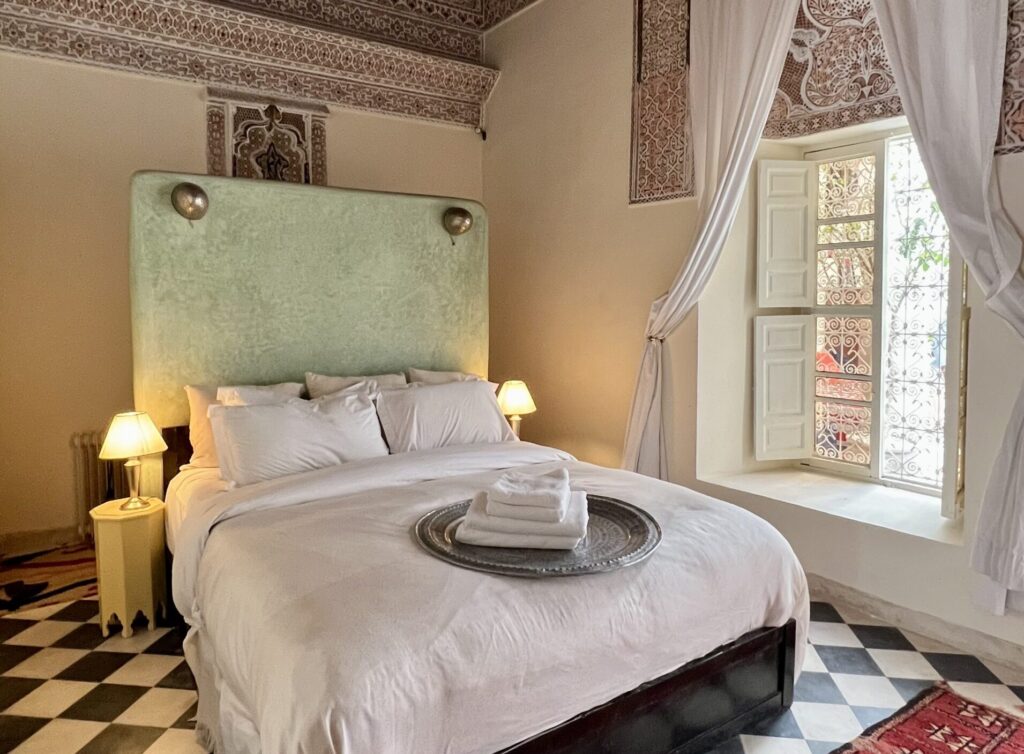 Riad Tizwa Marrakech room 6 view to the window, bed and traditional ornate plasterwork